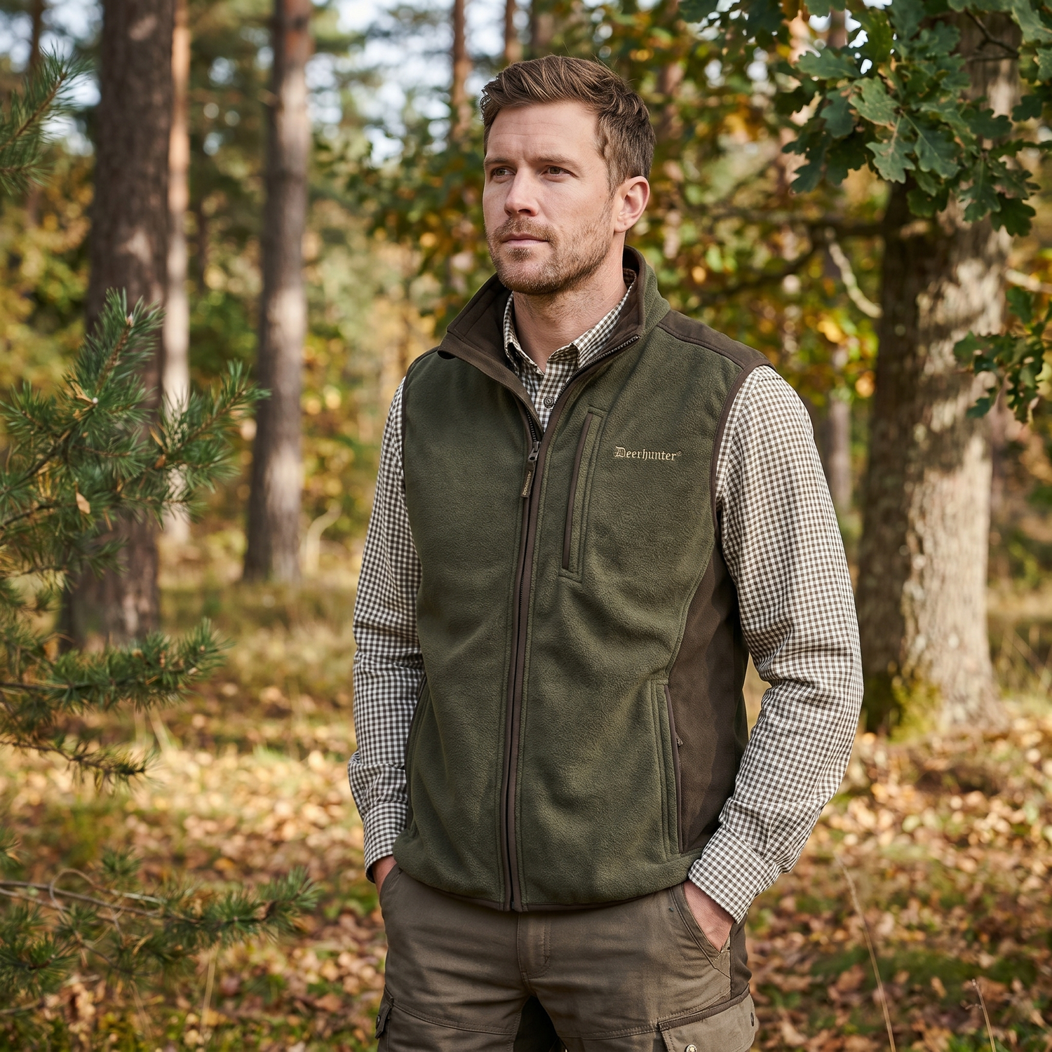 Man wearing a green vest and checkered shirt in a forest setting