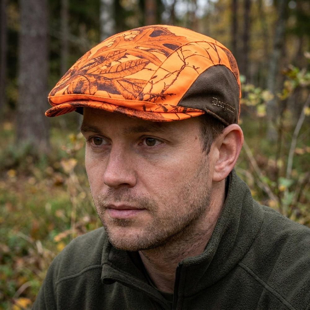 Man wearing an orange and brown camouflage cap in a forest setting