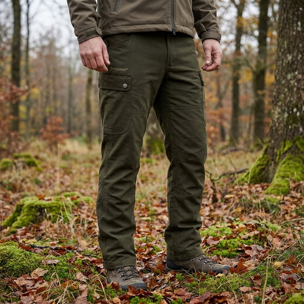 Person wearing green pants and a brown jacket in a forest setting